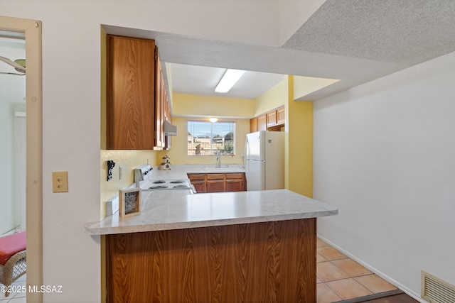 kitchen featuring kitchen peninsula, white fridge, light tile patterned floors, electric range oven, and sink