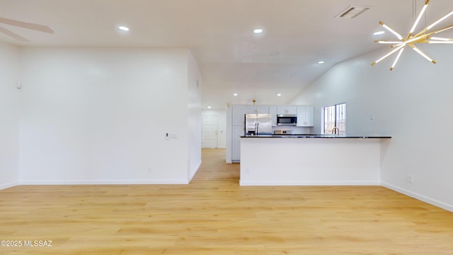 kitchen featuring stainless steel appliances, a notable chandelier, kitchen peninsula, white cabinets, and light wood-type flooring