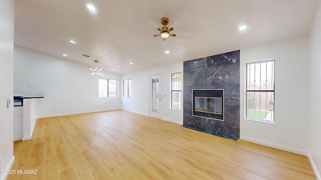 unfurnished living room with plenty of natural light, ceiling fan, light wood-type flooring, and a high end fireplace