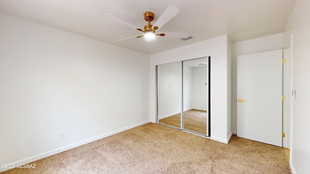 unfurnished bedroom featuring ceiling fan, a closet, and light colored carpet