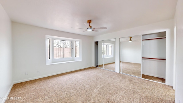 unfurnished bedroom featuring carpet flooring, two closets, and ceiling fan