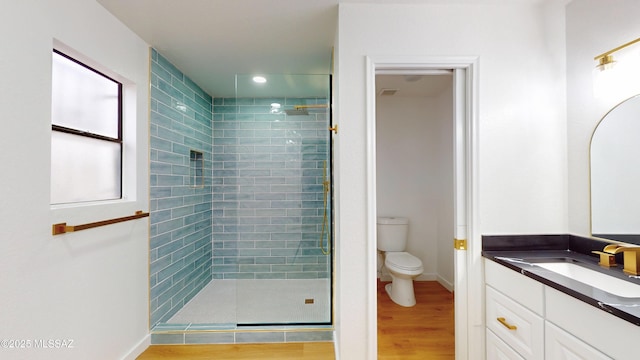 bathroom featuring hardwood / wood-style flooring, vanity, a shower with shower door, and toilet