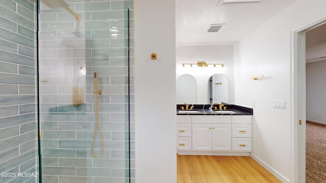 bathroom with hardwood / wood-style floors, vanity, and tiled shower