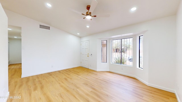 empty room with ceiling fan, light hardwood / wood-style floors, and vaulted ceiling