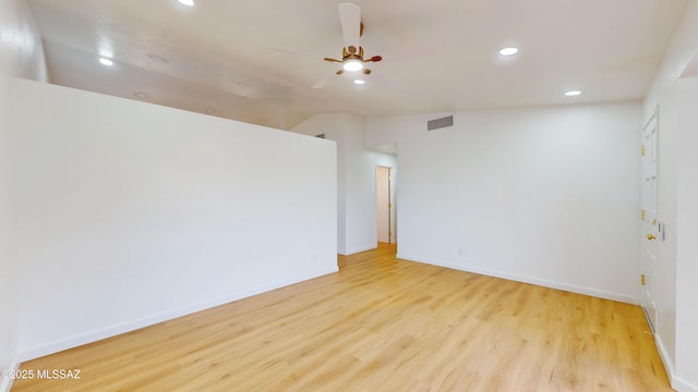 empty room with ceiling fan, light hardwood / wood-style floors, and vaulted ceiling