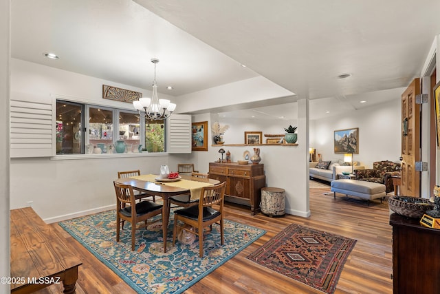 dining space with hardwood / wood-style floors and a notable chandelier