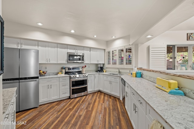 kitchen featuring sink, appliances with stainless steel finishes, dark hardwood / wood-style floors, light stone counters, and white cabinets