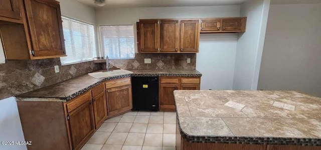 kitchen featuring light tile patterned floors, black dishwasher, tasteful backsplash, and sink