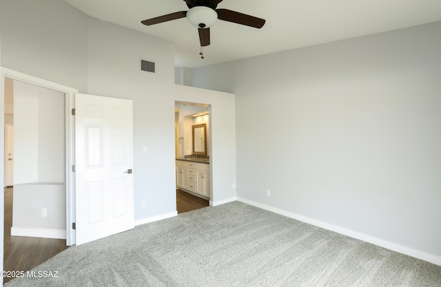 unfurnished bedroom with dark colored carpet, connected bathroom, high vaulted ceiling, and ceiling fan