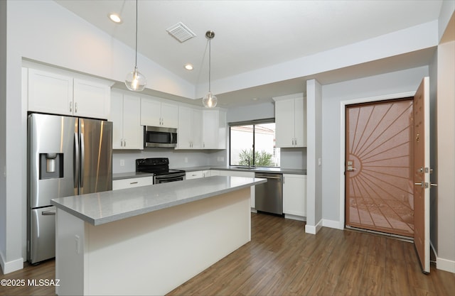 kitchen featuring white cabinetry, a center island, stainless steel appliances, pendant lighting, and vaulted ceiling