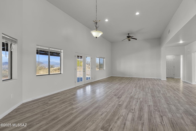 unfurnished living room featuring baseboards, a high ceiling, ceiling fan, and light wood finished floors