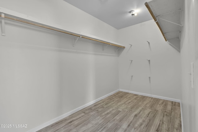walk in closet with wood finished floors