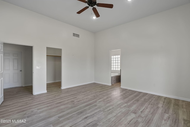 empty room featuring visible vents, baseboards, light wood-style floors, and ceiling fan