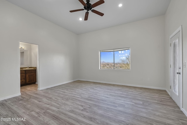 unfurnished bedroom with light wood-style flooring, a sink, recessed lighting, a high ceiling, and baseboards
