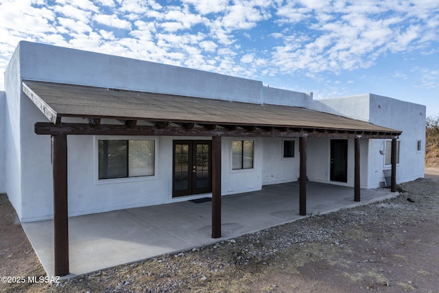rear view of property featuring french doors, a patio, and stucco siding