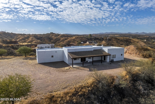 rear view of property featuring a mountain view and stucco siding