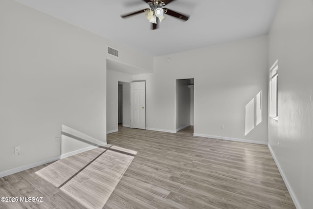 empty room featuring baseboards, light wood-style floors, visible vents, and ceiling fan