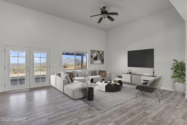 unfurnished living room featuring ceiling fan, a high ceiling, and light wood-type flooring