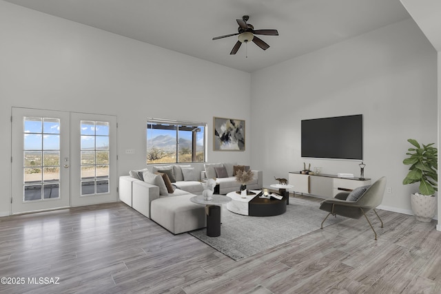 living room with ceiling fan, french doors, a high ceiling, and wood finished floors