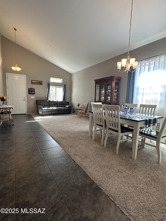 dining space featuring high vaulted ceiling, dark tile patterned floors, and an inviting chandelier