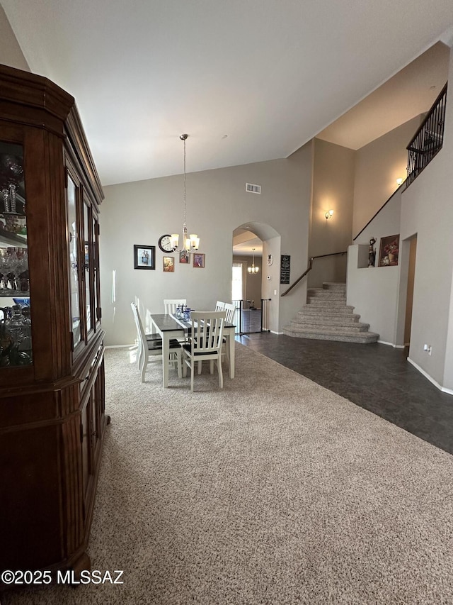 dining room featuring visible vents, arched walkways, stairway, dark colored carpet, and a notable chandelier