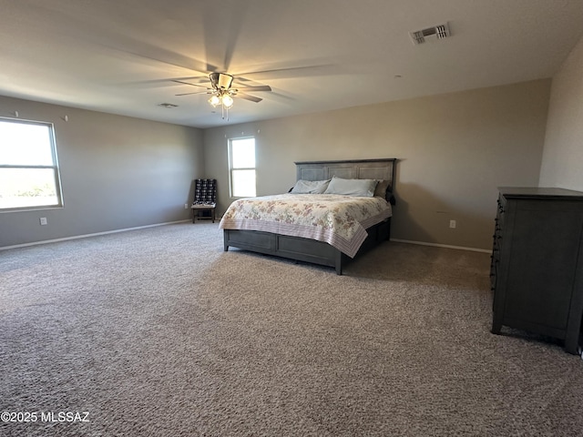 carpeted bedroom featuring a ceiling fan, multiple windows, visible vents, and baseboards