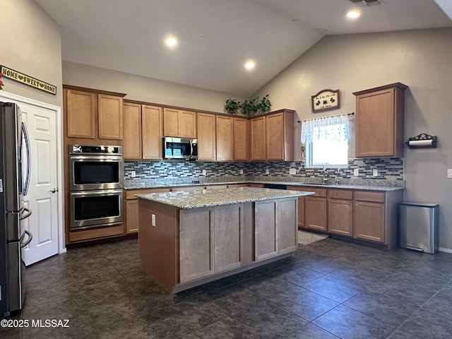 kitchen featuring lofted ceiling, light stone counters, stainless steel appliances, a center island, and decorative backsplash