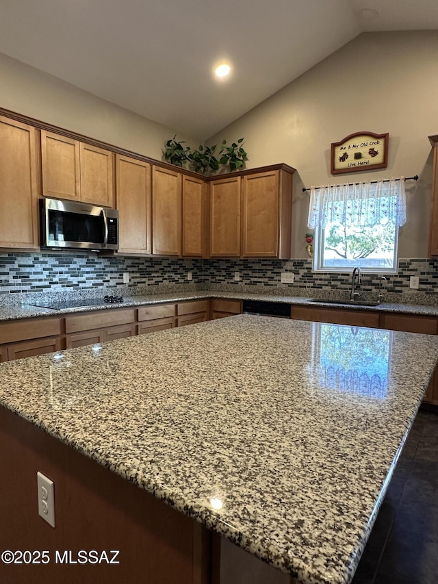 kitchen with black electric stovetop, stainless steel microwave, vaulted ceiling, and a center island