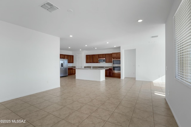 kitchen featuring appliances with stainless steel finishes, an island with sink, and light tile patterned flooring