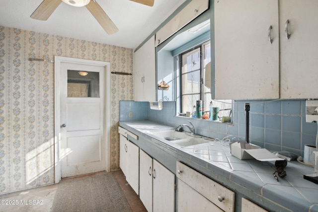 kitchen with white cabinets, sink, backsplash, tile countertops, and ceiling fan