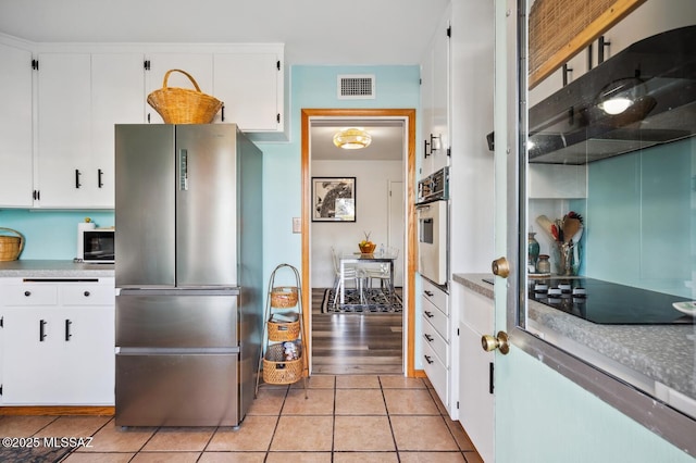 kitchen with white cabinetry, light tile patterned floors, and black appliances