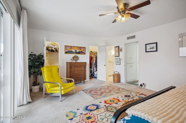 bedroom featuring light carpet, ensuite bathroom, ceiling fan, a spacious closet, and a closet