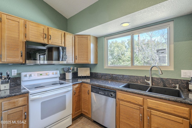 kitchen featuring light tile patterned flooring, vaulted ceiling, sink, stainless steel dishwasher, and electric range