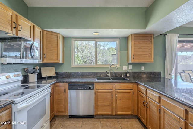 kitchen featuring stainless steel appliances, a wealth of natural light, sink, and dark stone countertops