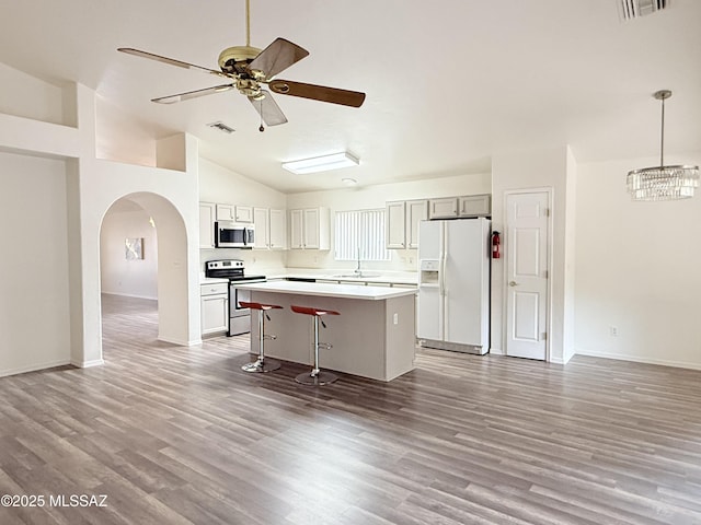 kitchen featuring a breakfast bar, stainless steel appliances, sink, pendant lighting, and a center island