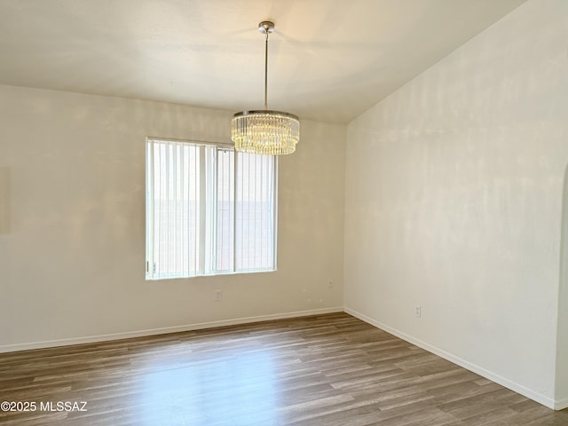 spare room with wood-type flooring and a notable chandelier