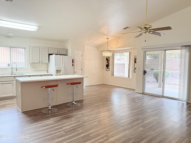 kitchen with ceiling fan, sink, light hardwood / wood-style floors, a kitchen island, and white fridge with ice dispenser