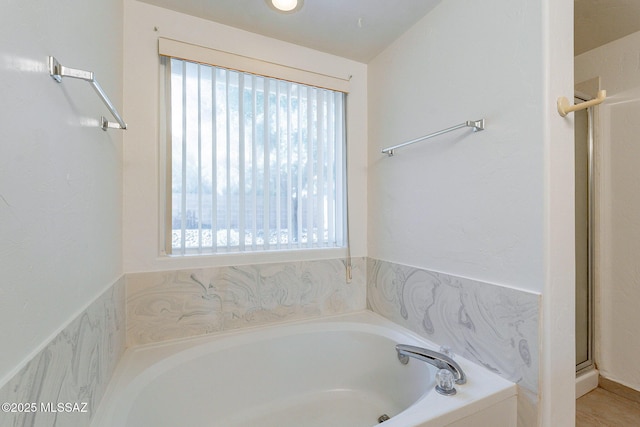 bathroom featuring plenty of natural light and tiled bath