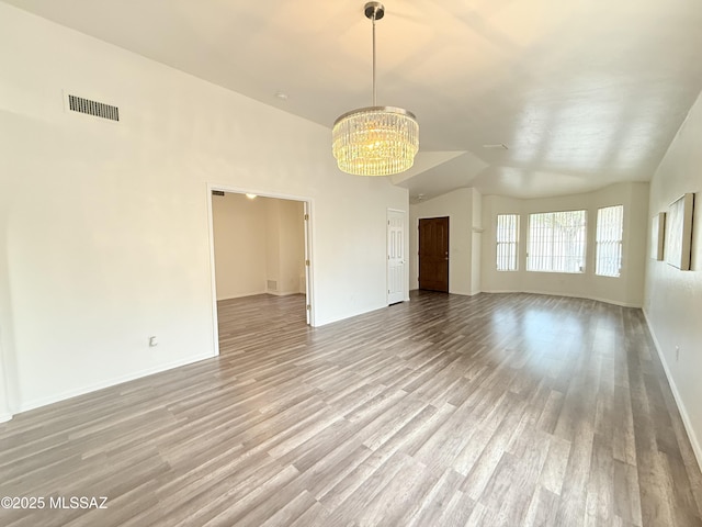 unfurnished living room with light hardwood / wood-style floors, an inviting chandelier, and lofted ceiling