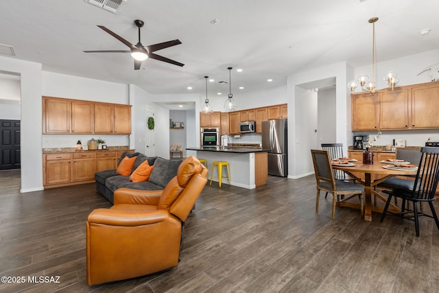 living room featuring sink, dark wood-type flooring, and ceiling fan with notable chandelier