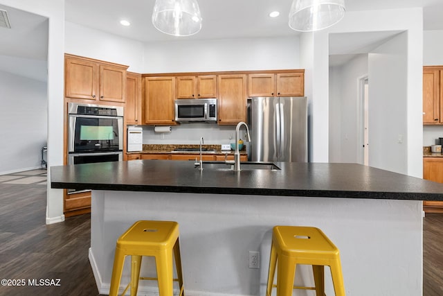 kitchen featuring hanging light fixtures, sink, a breakfast bar, a center island with sink, and stainless steel appliances