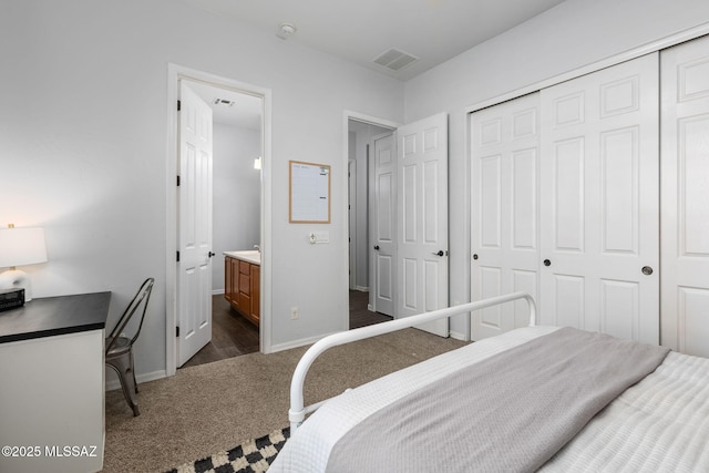 bedroom featuring dark colored carpet, a closet, and ensuite bath