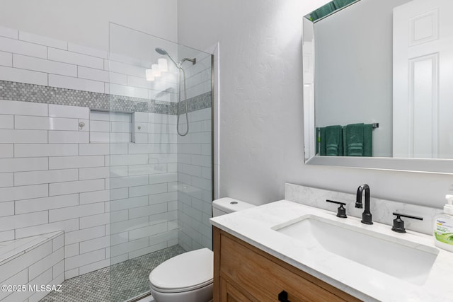 bathroom featuring vanity, toilet, and a tile shower