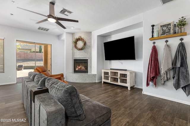 living room featuring ceiling fan and a tiled fireplace