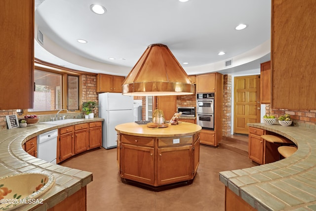 kitchen featuring tile countertops, island exhaust hood, a center island, white appliances, and sink