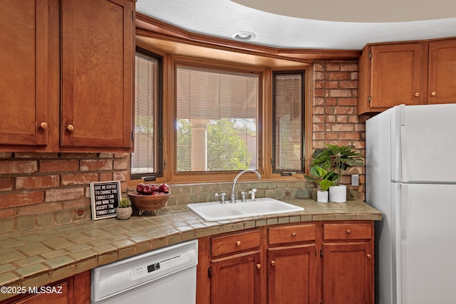 kitchen with tile counters, sink, decorative backsplash, and white appliances