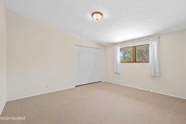 carpeted empty room with vaulted ceiling