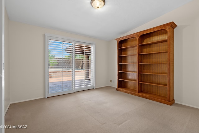 carpeted empty room featuring vaulted ceiling