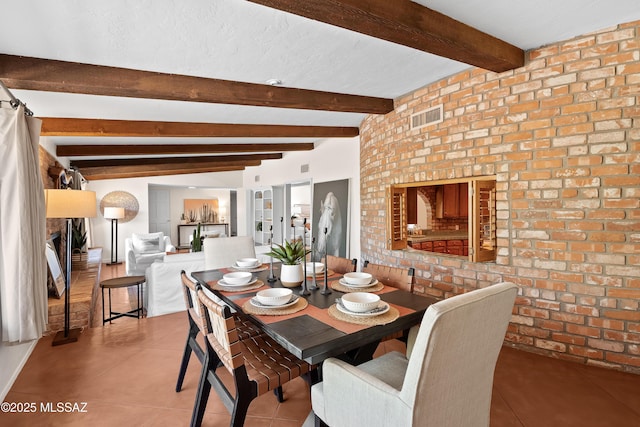 tiled dining space featuring brick wall and beam ceiling