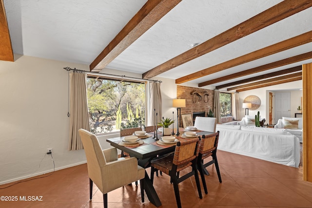 tiled dining room featuring a wealth of natural light, lofted ceiling with beams, a textured ceiling, and a fireplace